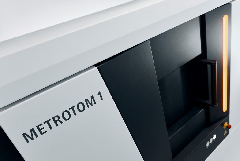 Angled view on a black and white CT scanner with an orange light turned on in the front